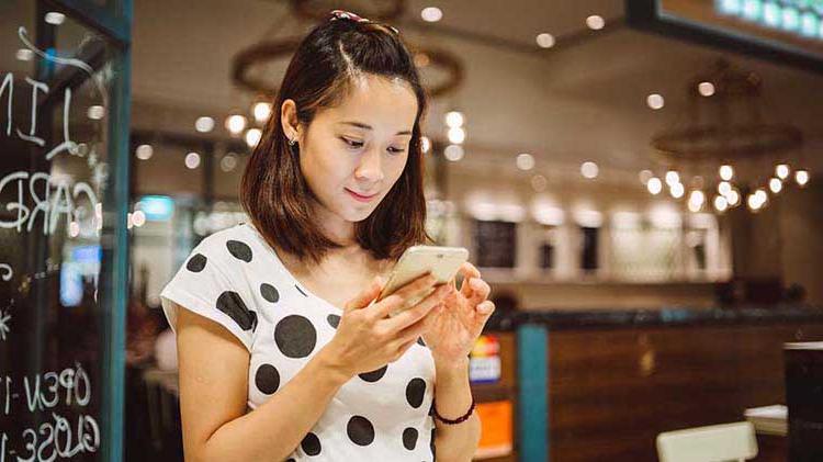 Woman looking at smartphone and accessing her files stored in the cloud.