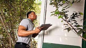 A man inspects the underside of a porch roof